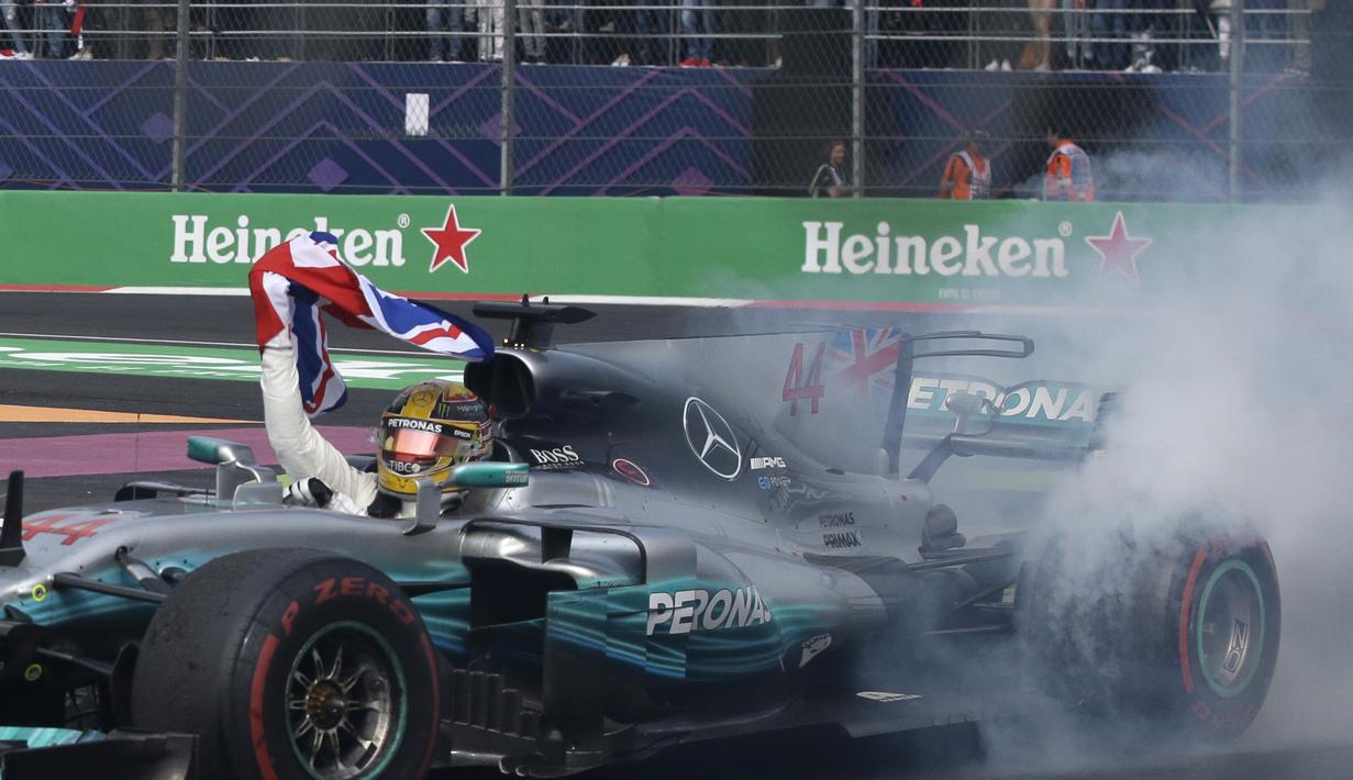 Lewis Hamilton mengibarkan bendera Inggris saat memastikan diri sebagai juara dunia F1 2017 di Hermanos Rodriguez racetrack, Mexico City, (29/10/20170). Hamilton finis kedelapan pada balapan tersebut.(AP/Rebecca Blackwell)