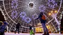 Pengunjung berjalan di dalam bola natal raksasa yang dipajang di Octyabrskaya Square dan dekorasi untuk menyambut perayaan Natal 2018 dan Tahun Baru 2019 di Minsk, Belarus, Selasa (18/12). (AP Photo/Sergei Grits)