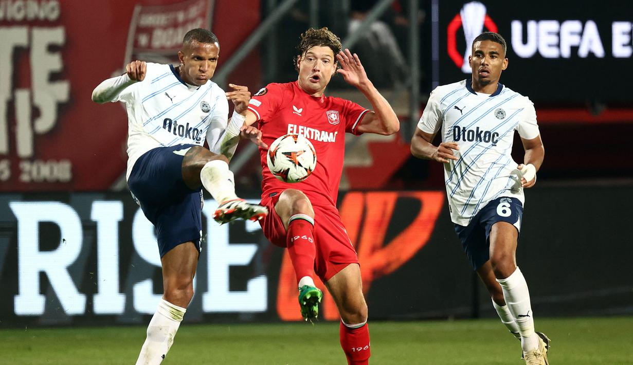 Pemain FC Twente, Sam Lammers (tengah) berebut bola dengan pemain Fenerbahce, Rodrigo pada laga Liga Europa 2024/2025 di FC Twente stadium, Enschede, Belanda, Jumat (04/10/2024) dini hari WIB. (AFP/Vincent Jannink)