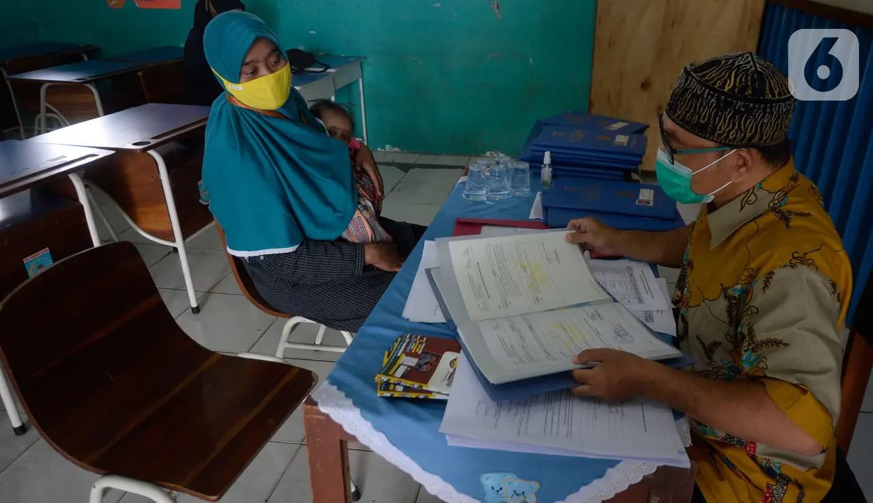 Guru Wali Kelas berdiskusi dengan wali murid saat pembagian raport di SMP Negeri 18 Tangerang Selatan, Banten, Kamis (17/12/2020). Menghindari terjadinya kerumunan, pembagian raport diatur waktunya sesuai kelas. (merdeka.com/Dwi Narwoko)