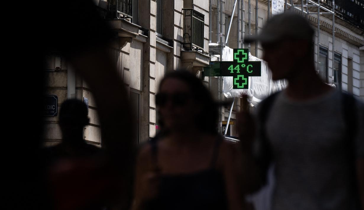<p>Pejalan kaki berjalan menyusuri jalan saat lampu apotek menunjukkan suhu turun 44 derajat celsius di Nantes, Senin (18/7/2022). Peramal cuaca menempatkan 15 departemen di sebagian besar sisi barat Prancis ke status siaga tertinggi untuk suhu ekstrem saat gelombang panas melanda negara itu dan akan mencapai puncaknya. (Loic VENANCE / AFP)</p>