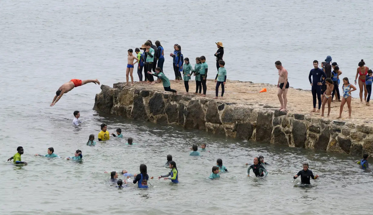 Anak-anak bermain air di Pantai Carcavelos, di luar Lisbon, Portugal, Selasa (12/7/2022). Suhu diperkirakan mencapai 46 derajat Celcius (115 Fahrenheit) di beberapa bagian negara Portugal pada Rabu. (AP Photo/Armando Franca)