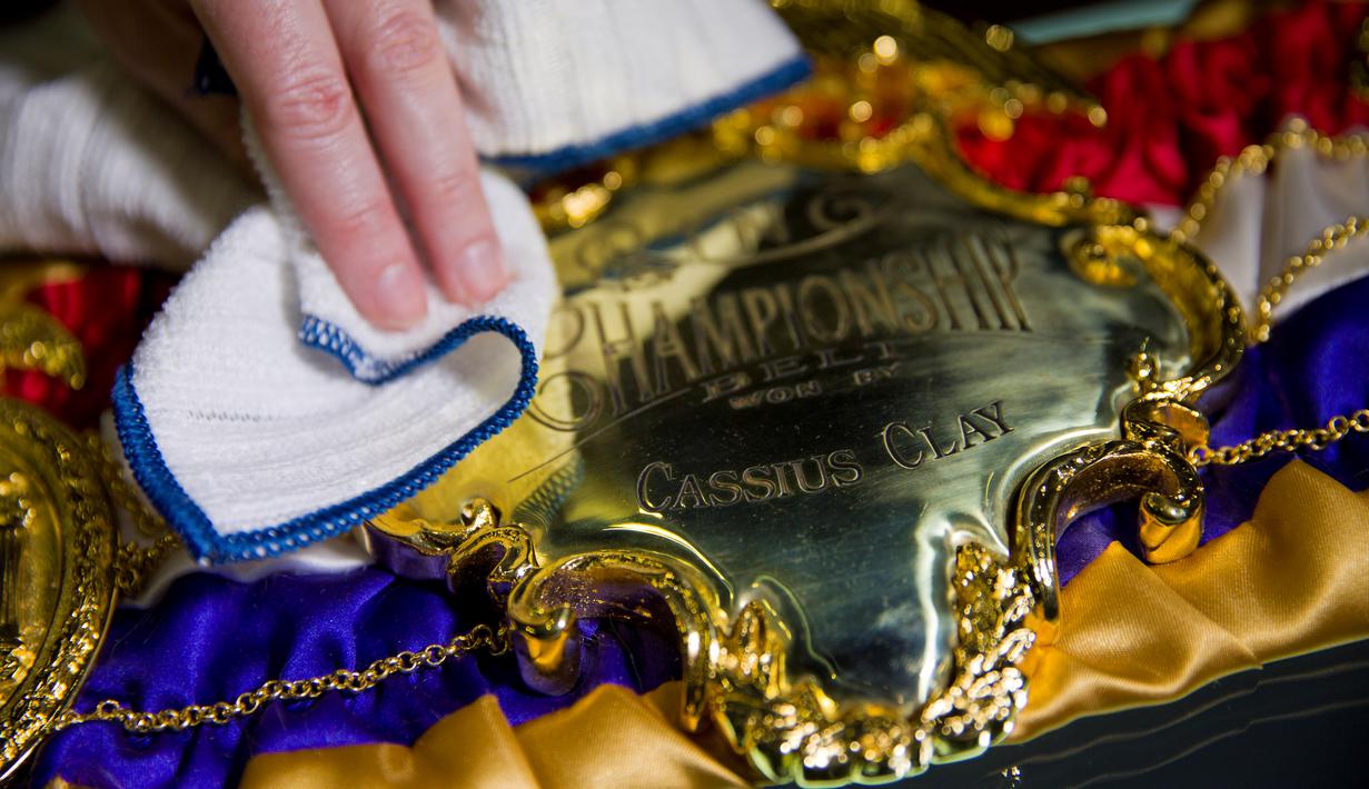 Seorang petugas membersihkan replika sabuk juara Cassius Clay tahun 1964 jelang pameran perjalanan hidup Muhammad Ali dengan judul "I Am The Greatest" di O2 Arena, London, Inggris, (3/3/2016). (AFP/Justin Tallis)