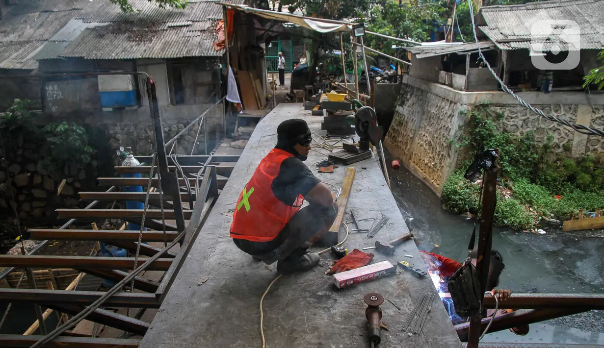 Pekerja menyelesaikan proyek pembangunan jembatan penghubung antarkampung di kawasan Pondok Pinang, Jakarta, Jumat (13/12/2019).  Jembatan yang menghubungkan permukiman di daerah Pondok Pinang dengan kawasan Bintaro tersebut ditargetkan rampung pada akhir Desember. (Liputan6.com/Faizal Fanani)