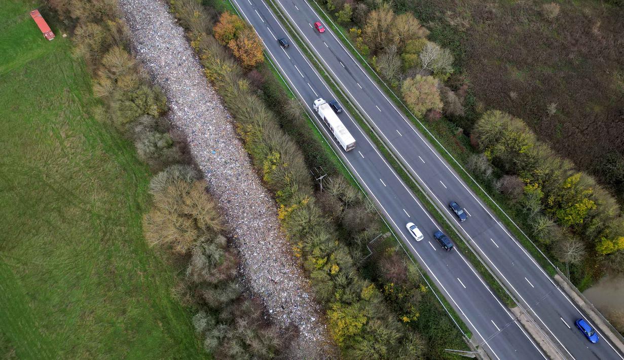 Diperkirakan, biaya pembersihan tumpukan sampah tersebut mencapai sekitar 25 juta poundsterling (Rp 550 miliar), angka ini melampaui anggaran tahunan dewan lokal. Tampak foto udara memperlihatkan tumpukan besar sampah yang dibuang sembarangan, yang ditumpahkan di sebuah ladang antara Sungai Cherwell dan Jalan Raya A34 dekat Kidlington, Oxfordshire, di barat London pada 16 November 2025. (Justin TALLIS/AFP)
