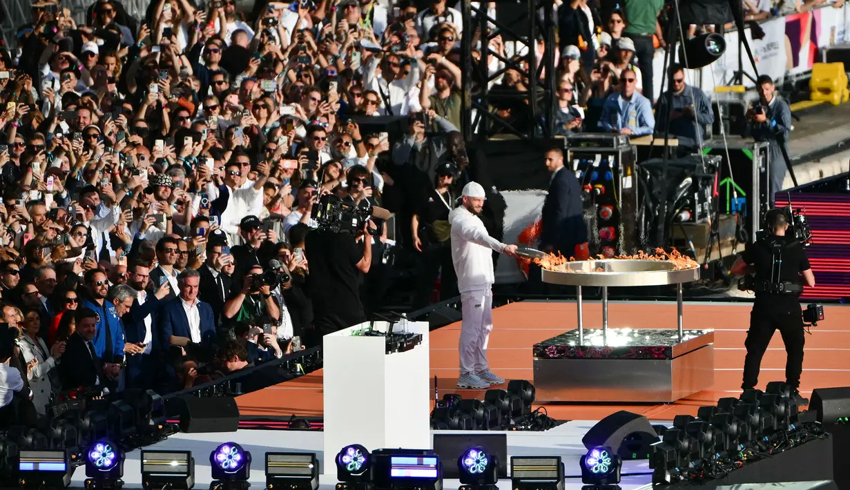 Rapper Prancis, Julien Mari alias Jul lights menyalakan api di kuali relai obor saat upacara penyambutan kedatangan api Olimpiade dan Paralimpiade Paris 2024 di Vieux-Port (Pelabuhan Tua) Marseille, Pranci, Rabu (08/05/2024) waktu setempat. (AFP/Christophe Simon)