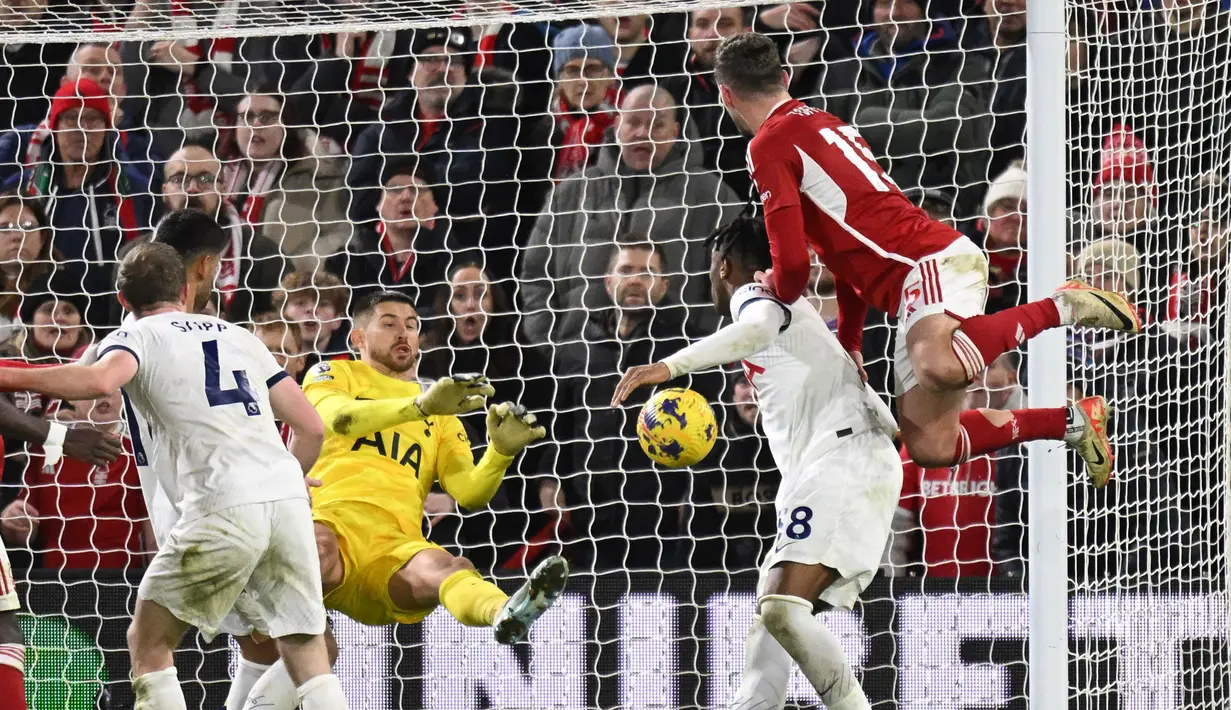 Kiper Tottenham Hotspur asal Italia, Guglielmo Vicario (dua kiri), berhasil menghalau bola sundulan dari pemain Nottingham Forest, Harry Toffolo (kanan), dalam pertandingan pekan ke-17 Liga Inggris 2023/2024 yang berlangsung di The City Ground, Sabtu (16/12/2023) dini hari WIB. (AFP/Oli Scarff)