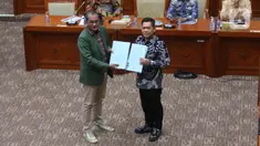 Wakil Menteri Hukum dan HAM Edward Omar Sharif Hiariej (kiri) saat menyerahkan naskah RUU KUHP dan RUU tentang Permasyarakatan yang telah disempurnakan kepada Wakil Ketua Komisi III DPR Adies Kadir (kanan) saat rapat kerja bersama Komisi III DPR di Kompleks Parlemen, Senayan, Jakarta, Rabu (6/7/2022). (Liputan6.com/Angga Yuniar)