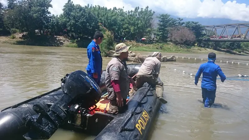 Petugas gebungan sedang mengamati keberadaan buaya berkalung ban target di Sungai Palu, Sabtu (8/2/2020). (Foto: Liputan6.com/Heri Susanto)