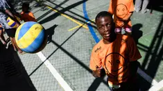 Seorang anak mencoba melambungkan bola voli pada program Volleyball Development Training yang digagas oleh FIVB di Formiga favela, Rio de Janeiro, (2/8/2016). (AFP/Leon Neal)