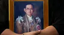 Seorang warga memegang foto Raja Bhumibol Adulyadej jelang pemindahan jenazah ke Grand Palace, Bangkok, Thailand, Jumat (14/10). (REUTERS / Athit Perawongmetha)