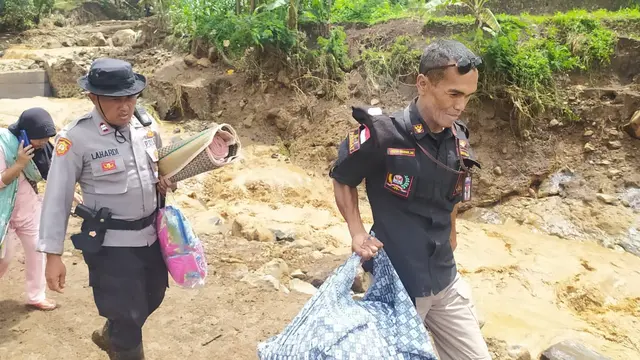 Nampak dua anggota Kepolisian Resort Garut, tengah memberikan pertolongan membawa beberapa barang milik warga setelah musibah banjir bandang di wilayah Kecamatan Karangtengah.