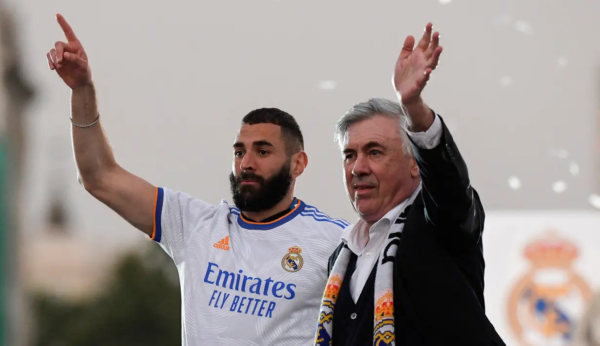 <p>Pelatih Real Madrid, Carlo Ancelotti dan penyerang Karim Benzema melambai kepada suporter saat merayakan trofi La Liga Spanyol di alun-alun Plaza Cibeles di Madrid pada 30 April 2022. Real Madrid mengamankan gelar La Liga ke-35  setelah kemenangan kandang 4-0 atas Espanyol. (AFP/Oscar Del Pozo)</p>