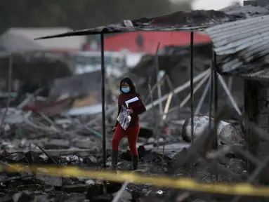 Seorang wanita berjalan di antara puing-puing bangunan rumah yang hancur dalam ledakan pasar kembang api terbesar di luar Ibu Kota Meksiko, Selasa (20/12). Sedikitnya 27 orang tewas dan lebih dari 70 lainnya terluka. (REUTERS/Edgard Garrido)