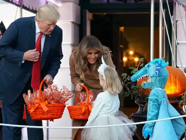 Presiden AS, Donald Trump dan Ibu Negara, Melania Trump membagikan permen kepada anak-anak saat open house perayaan pesta Halloween di Gedung Putih, Senin (30/10). Para siswa dan orang tua dari 20 sekolah hadir di acara ini. (AP/Pablo Martinez Monsivais)