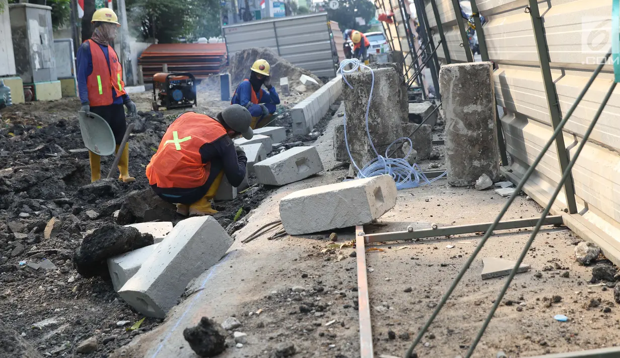 Aktivitas pekerja menyelesaikan proyek revitalisasi trotoar di Jalan Salemba Raya, Jakarta, Jumat (6/9/2019). Proyek revitalisasi trotoar dengan anggaran Rp 75 miliar ini ditargetkan rampung pada Desember mendatang. (Liputan6.com/Helmi Fithriansyah)