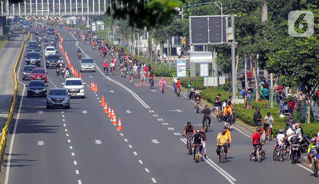 Warga berolahraga menggunakan sepeda di sepanjang Jalan Sudirman, Jakarta, Minggu (26/7/2020). Pemprov DKI menyiapkan 30 kawasan khusus pesepeda di lima kota administrasi Jakarta. (Liputan6.com/Faizal Fanani)