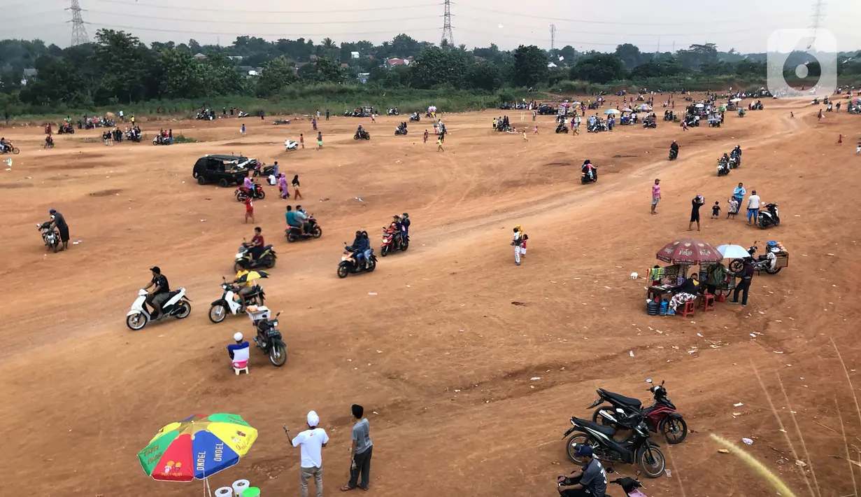 Warga menghabiskan waktu di tanah lapang kawasan Cipayung, Depok, Kamis (11/6/2020). Kurang tegasnya sanksi serta minimnya kesadaran masyarakat akan protokol kesehatan terkait covid-19 menyebabkan kawasan itu menjadi tempat berkerumun warga setiap sore hari. (Liputan6.com/Immanuel Antonius)