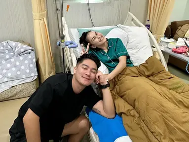 Boy William menggenggam tangan Ayu Ting Ting yang sedang berbaring di ranjang perawatannya. (Foto: Instagram/ ayutingting92)