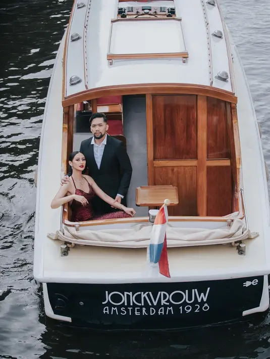 Di salah satu fotonya, Ayu dan calon suami berada di atas kapal yang berada di kanal. Wanita 25 tahun itu tampak menawan dan elegan dengan gaun berwarna merah. Sedangkan sang kekasih terlihat gagah dengan setelan jas berwarna hitam. (Liputan6.com/IG/@ayumaulida97)