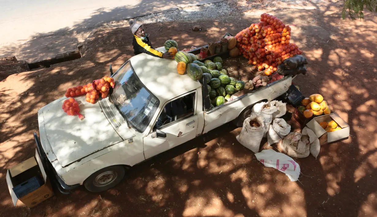 Seorang pria menata buah dan sayuran di mobilnya saat berjualan di sisi jalan yang sibuk di Harare, 7 Juli 2020. Mobil menjadi pasar bergerak di mana penduduk Zimbabwe menjual barang dagangan dari kendaraan untuk mengatasi kesulitan ekonomi yang disebabkan Covid-19 (AP Photo/Tsvangirayi Mukwazhi)