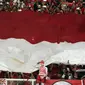 Suporter membentangkan bendera Merah Putih raksasajelang menyaksikan laga Timnas Indonesia U-19 melawan Jepang U-19 pada perempat final Piala AFC U-19 2018 di Stadion GBK, Jakarta, Minggu (28/10). Indonesia kalah 0-2. (Liputan6.com/Helmi Fithriansyah)