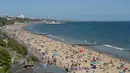 Orang-orang menikmati sinar matahari di pantai dekat Dermaga Bournemouth di Bournemouth, Inggris, Senin (25/5/2020). Inggris mulai melonggarkan beberapa pembatasan yang diberlakukan untuk mengendalikan penyebaran virus corona Covid-19. (Photo by Glyn KIRK / AFP)