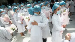 Perawat berpelukan saat upacara peringatan Hari Perawat Internasional di Rumah Sakit Tongji, Wuhan, Provinsi Hubei, China, Selasa (12/5/2020). Menurut WHO, perawat berada di garis depan dalam memerangi pandemi virus corona COVID-19. (STR/AFP)