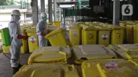 Petugas menyemprotkan cairan disinfektan pada "Wheeled Bin" atau tempat sampah berisi limbah B3 medis Infeksius Covid-19 usai dimusnahkan dengan mesin incinerator di PT Jasa Medivest, Karawang, Jawa Barat, Kamis (10/12/2020).  (Liputan6.com/Herman Zakharia)