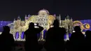 Pengunjung mengambil gambar bangunan ikonik kota Sharjah yang diterangi lampu warna-warni selama festival cahaya Sharjah di Uni Emirat Arab, 13 Februari 2019. Festival cahaya tahunan ini menampilkan kombinasi desain cahaya tiga dimensi. (KARIM SAHIB/AFP)