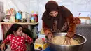 Di setiap negara, roti ini bisa memiliki variasi bentuk dan rasa yang sedikit berbeda. Tampak dalam foto, seorang wanita mengaduk adonan saat menyiapkan biskuit tradisional "kaak" yang berbentuk cincin menjelang Idul Fitri, hari raya yang menandai berakhirnya bulan puasa suci Ramadan, di Kota Gaza pada 16 Maret 2026. (Omar AL-QATTAA/AFP)