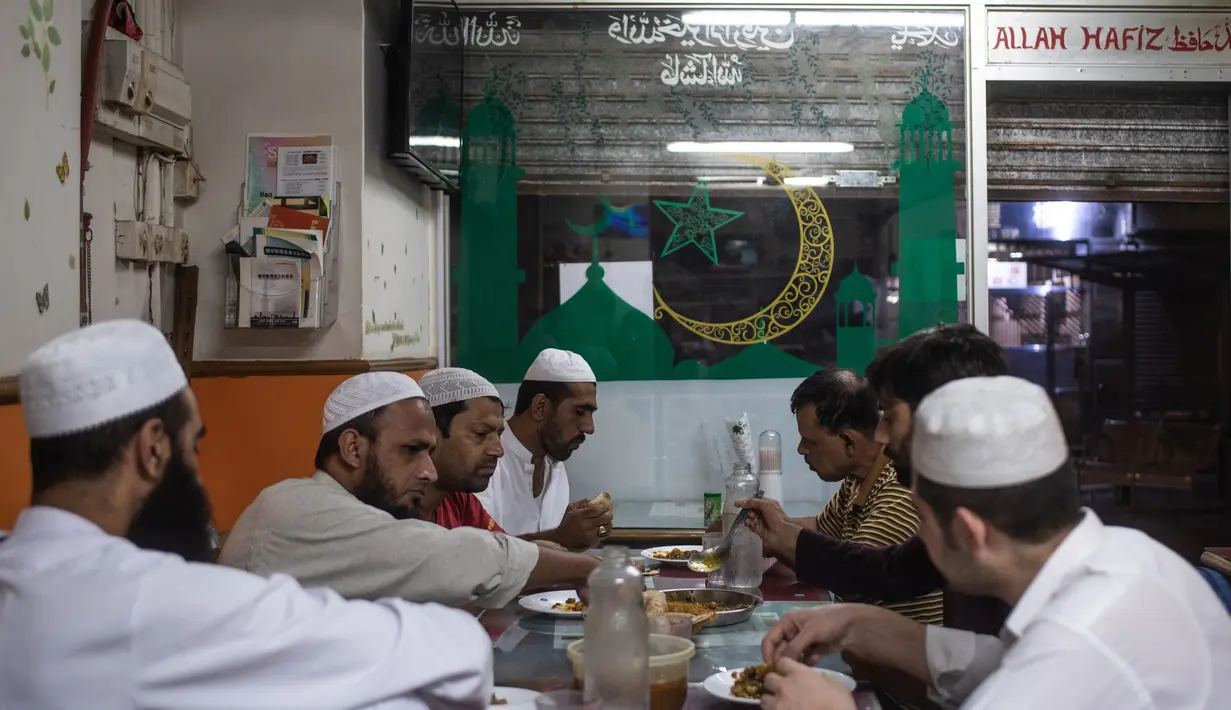 Para imigran Pakistan menikmati makanan sahur sebelum beribadah puasa di distrik Kwai Chung di Hong Kong (25/5/2019). Kwai Chung adalah daerah perkotaan di dalam Kota Baru Tsuen Wan di Wilayah Baru Hong Kong. (AFP Photo/Philip Fong)