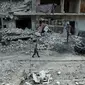 Seorang pria berjalan di antara kehancuran parah akibat  serangan udara rezim pemerintah Suriah di Ghouta Timur, Minggu (25/2). Sekjen PBB António Guterres menggambarkan kondisi di Ghouta timur saat ini sebagai "neraka di bumi". (HAMZA AL-AJWEH/AFP)