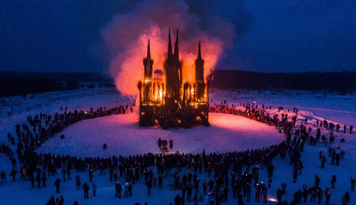 Sejumlah warga menonton bangunan bergaya gothik karya seniman Nikolay Polissky yang dibakar saat perayaan Shrovetide di wilayah Kaluga, Rusia (17/2). Perayaan ini menandai berakhirnya musim dingin yang dirayakan sejak masa pagan. (AFP/Dmitry Serebryakov)