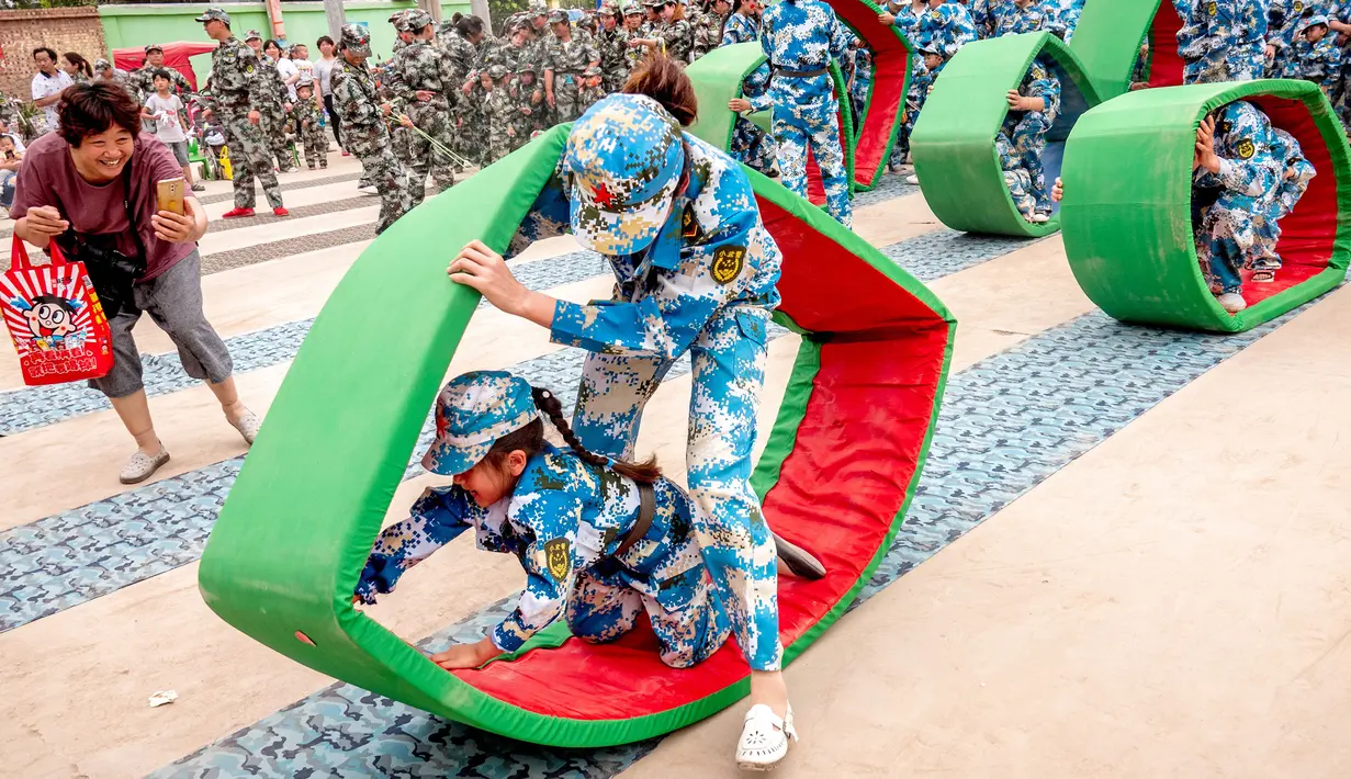 Sejumlah anak-anak melakukan simulasi latihan militer di sebuah taman kanak-kanak di provinsi Henan, China (30/5). Latihan militer ini dilakukan untuk menjelang Hari Anak Internasional yang jatuh pada 1 Juni. (AFP)