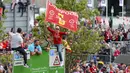 Seorang fans mengibarkan bendera Liverpool saat parade juara Liga Champions 2019 di Liverpool, Minggu (2/6). Ribuan fans tumpah ruah di jalanan untuk merayakan keberhasilan pemain membawa pulang trofi Si Kuping Besar ke kota Liverpool. (AP/Danny Lawson)