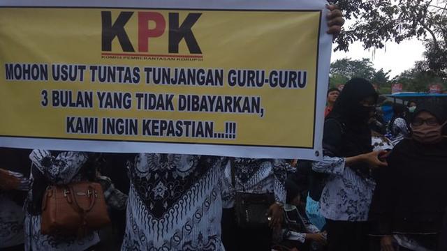 Seorang guru membawa beleho menuntut KPK mengusut tidak dibayarkannya TPP di Kota Pekanbaru.