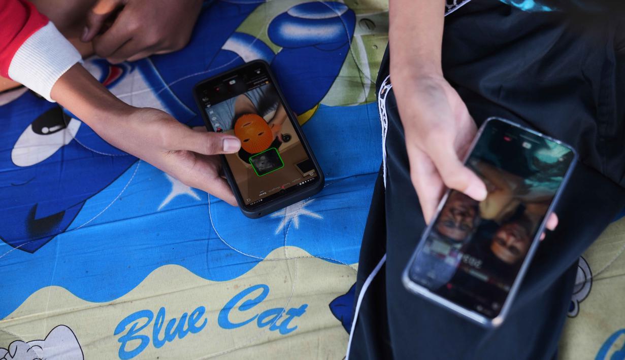 Langkah ini menjadi bagian dari upaya Pemerintah Indonesia untuk memastikan ruang digital yang aman bagi anak-anak. Tampak dalam foto, remaja laki-laki menggunakan ponsel mereka untuk menjelajahi media sosial di Jakarta, 16 Maret 2026. (AP Photo/Dita Alangkara)