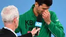 Petenis Serbia, Novak Djokovic, menangis saat diwawancara tentang Kobe Bryant seusai laga Australia Open 2020 di Melbourne, Selasa (28/1). Beri penghormatan dirinya memakai jaket inisial Kobe Bryant. (AFP/William West)