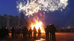 Peserta menyaksikan kembang api menjelang perayaan "Jeongwol Daeboreum" di Seoul, Korea Selatan (1/3). Jeongwol Daeboreum merupakan perayaan hari libur tradisional Korea untuk merayakan bulan purnama pertama kalender lunar. (AFP Photo/Jung Yeon-je)