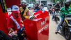 Seorang pekerja SPBU (kiri) menerima pembayaran dari pengendara yang mengantre untuk mengisi bahan bakar sepeda motor mereka di sebuah Stasiun Pengisian Bahan Bakar Umum (SPBU), Jakarta pada Rabu 1 April 2026. Pemerintah resmi tidak mengubah harga Bahan Bakar Minyak (BBM) di dalam negeri, baik harga BBM subsidi maupun non subsidi. (BAY ISMOYO/AFP)