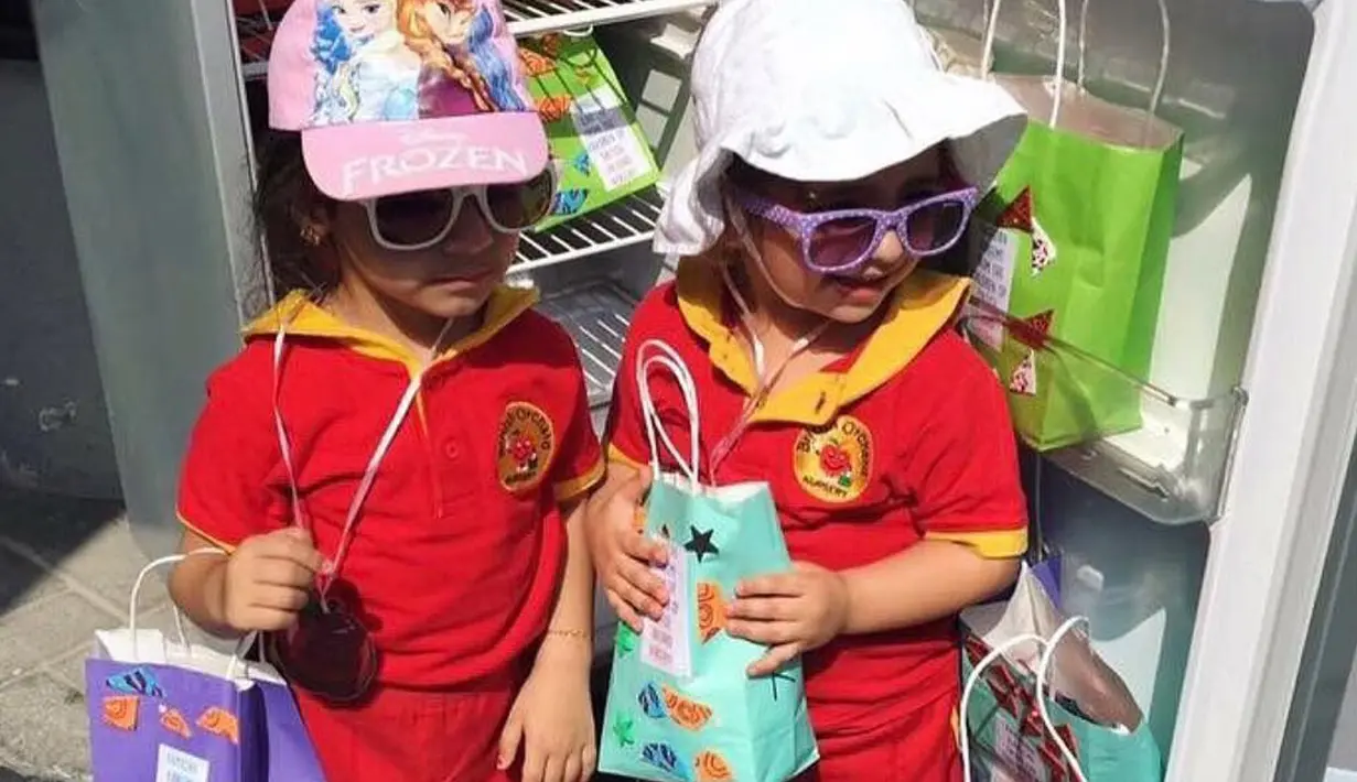 Dua orang anak berfoto di depan kulkas sambil memegang bungkus yang berisi makanan dan minuman jelang bulan Ramadan di Dubai. Kulkas ini disediakan untuk pekerja dan buruh yang akan berbuka puasa di bulan Ramadan. (www.instagram.com/ramadanfridgesdxb)