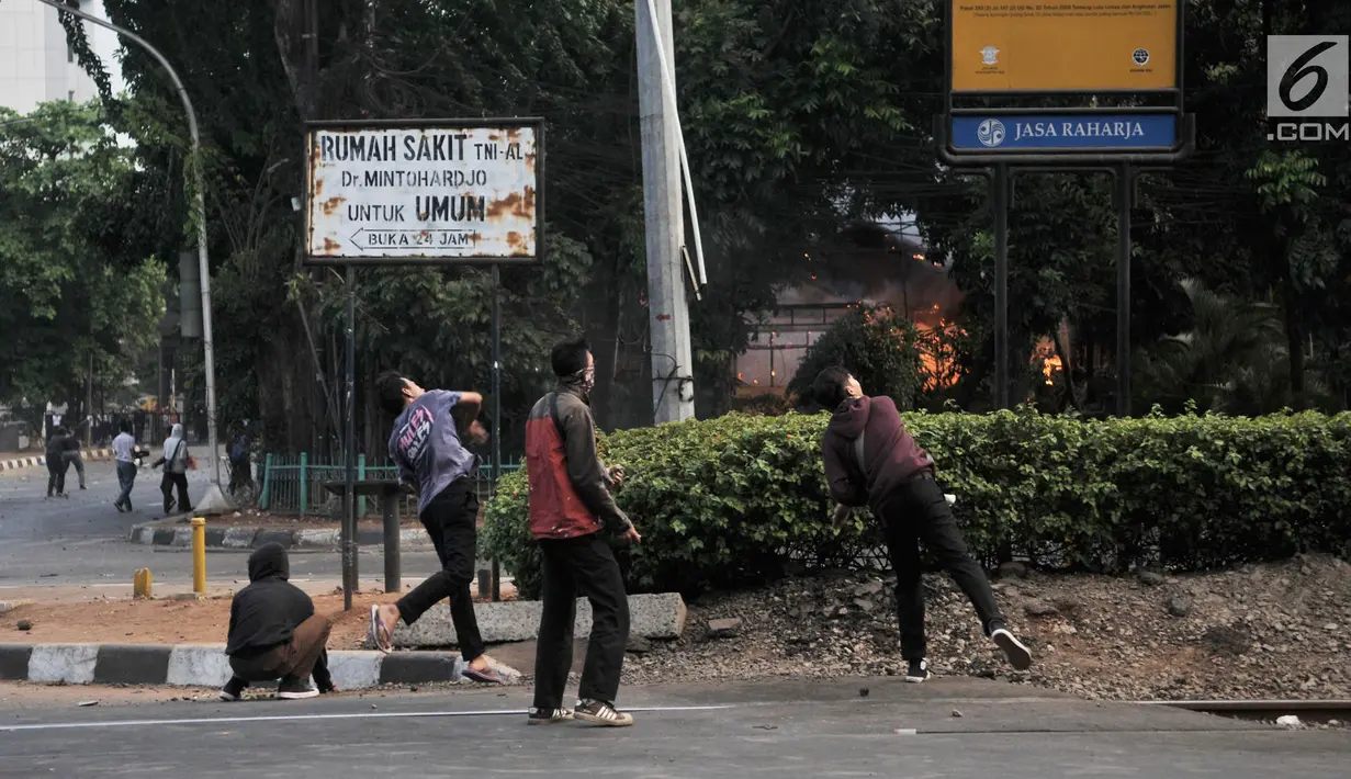 Massa melempari batu ke arah polisi saat Pos Polisi Subsektor Pejompongan terbakar dalam demonstrasi yang berujung bentrok di Jakarta, Rabu (25/9/2019). Pos Polisi Subsektor Pejompongan yang berada dekat lokasi bentrok terbakar hingga menghanguskan bangunan. (merdeka.com/Iqbal Nugroho)
