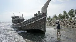 Seorang warga menarik tali di atas perahu kayu yang digunakan warga Rohingya di Pidie, Provinsi Aceh pada 27 Desember 2022. Pengungsi Rohingya menerima perawatan medis darurat setelah sebuah kapal yang membawa hampir 200 orang mendarat di Indonesia pada 26 Desember, kata pihak berwenang, dalam pendaratan keempat di negara dalam beberapa bulan terakhir. (AFP/Amanda Jufrian)