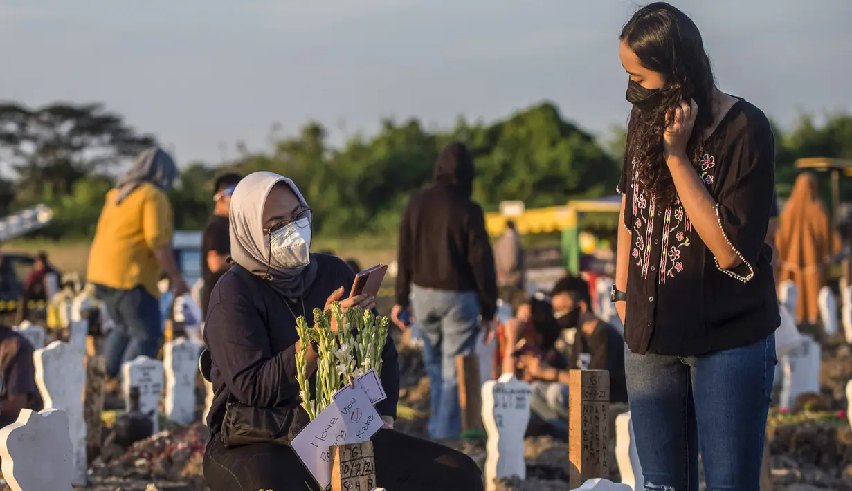 Keluarga berdoa untuk kerabat mereka di lokasi pemakaman korban virus corona COVID-19 di TPU Keputih, Surabaya, Jawa Timur, Sabtu (17/7/2021). Di Kota Surabaya terdapat dua tempat lahan pemakaman khusus blok COVID-19 yakni TPU Keputih dan TPU Babat Jerawat. (JUNI KRISWANTO/AFP)