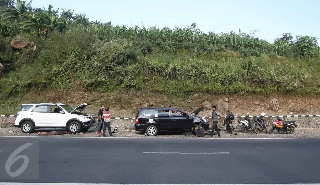 Dua mobil yang rusak tengah diperbaiki oleh montir di Jalan Warung Peuteuy, Garut, Jabar, Senin (4/7). Banyaknya kendaraan pemudik yang rusak menjadi berkah bagi para montir panggilan tersebut. (Liputan6.com/Immanuel Antonius)