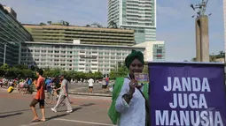 Seorang aktivis membentangkan spanduk tertulis 'janda juga manusia' saat melakukan aksi peringatan Hari Ibu di Bundaran HI, Jakarta, Minggu (21/12/2014). (Liputan6.com/Herman Zakharia)