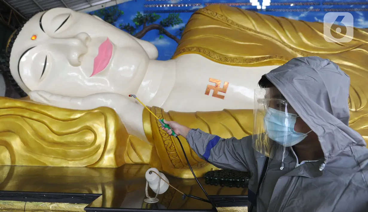 Petugas menyemprotkan cairan disinfektan ke patung Buddha tidur raksasa di Vihara Buddha Dharma dan 8 Posat, Bogor, Jawa Barat, Minggu (7/2/2021). Patung buddha tidur raksasa sepanjang 18 meter dan tinggi 5 meter tersebut dibersihkan setiap tahun menjelang Tahun Baru Imlek. (merdeka.com/Arie Basuki)