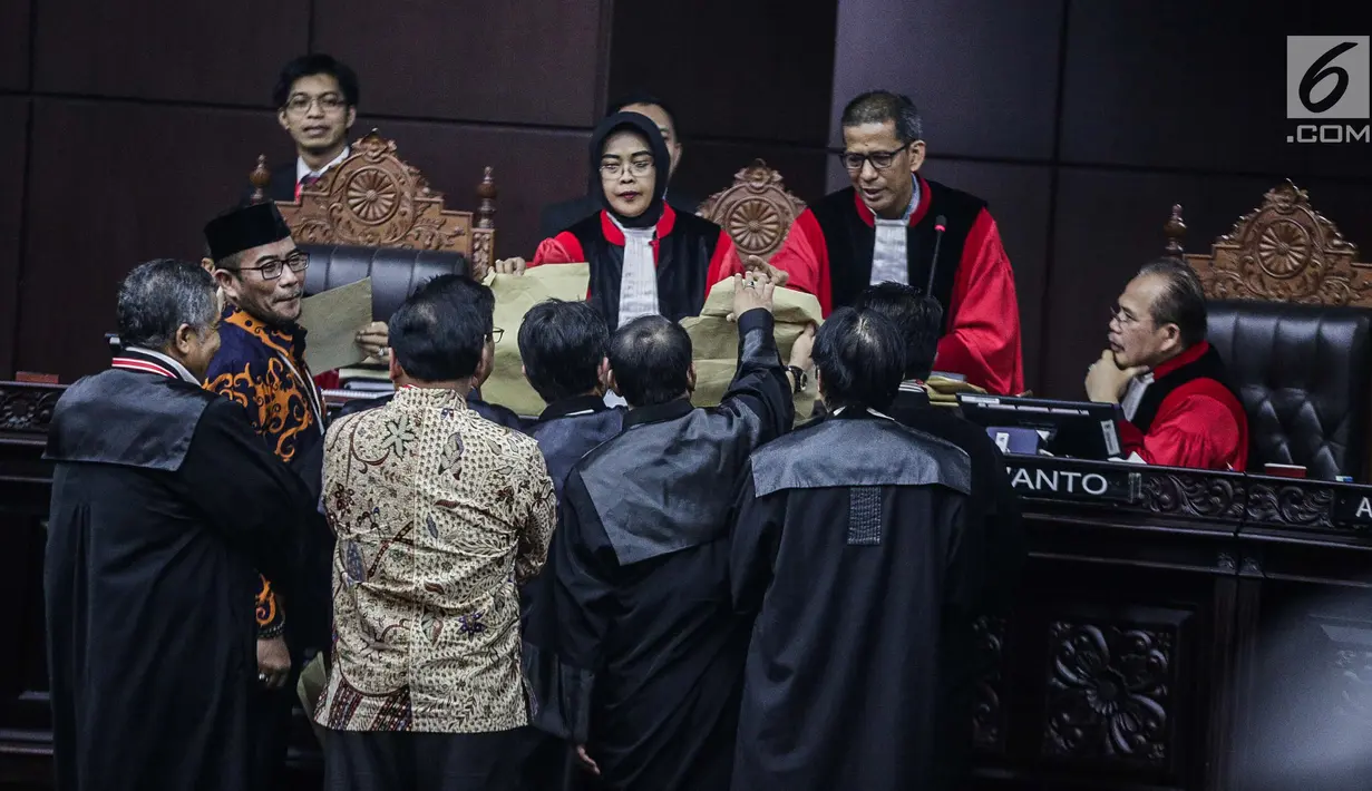 Komisioner KPU, Hasyim Asyari mengantar amplop kehadapan Majelis Hakim dan mendeskripsikan perbedaannya dalam sidang sengketa pilpres 2019 di Gedung MK, Jakarta, Kamis (20/6/2019). Hasyim mengatakan, ada kode-kode tertentu di tiap amplop yang menunjukkan fungsinya. (Liputan6.com/Faizal Fanani)
