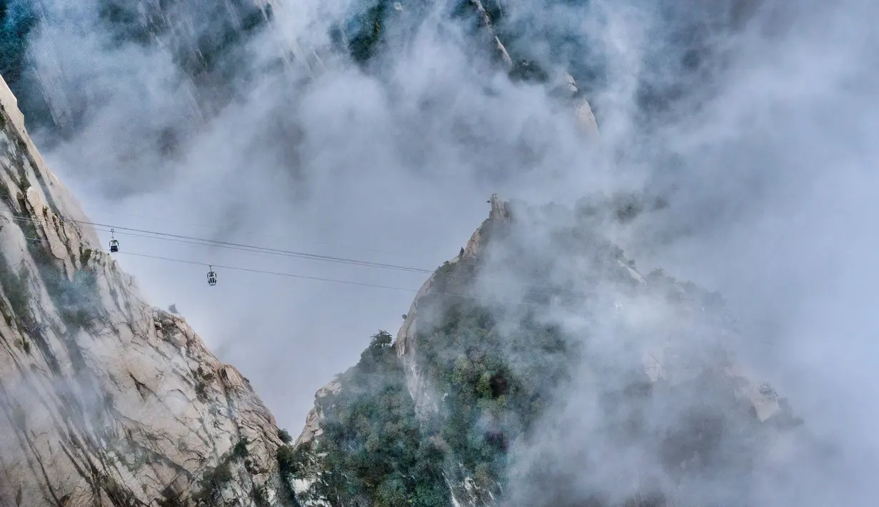 Foto dari udara yang diabadikan pada 20 September 2020 ini menunjukkan kereta gantung yang beroperasi di Gunung Huashan yang diselimuti kabut di Kota Weinan, Provinsi Shaanxi, China barat laut. (Xinhua/Tao Ming)